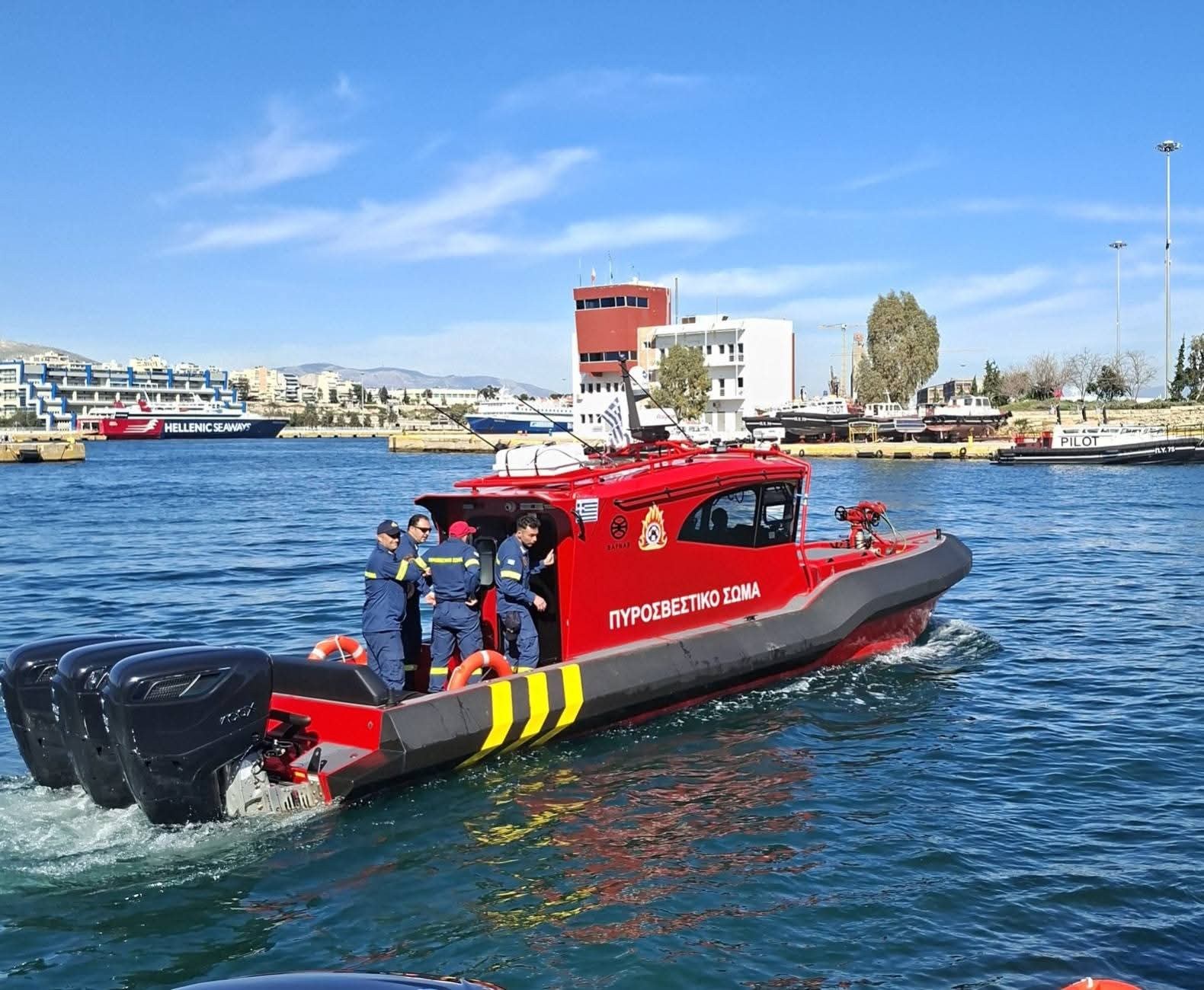 Red Rafnar fire fighting vessel with crew and three outboard engines underway in a harbour